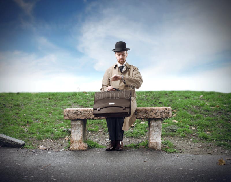 Gentleman sitting on a stone bench and looking at his watch. Gentleman sitting on a stone bench and looking at his watch