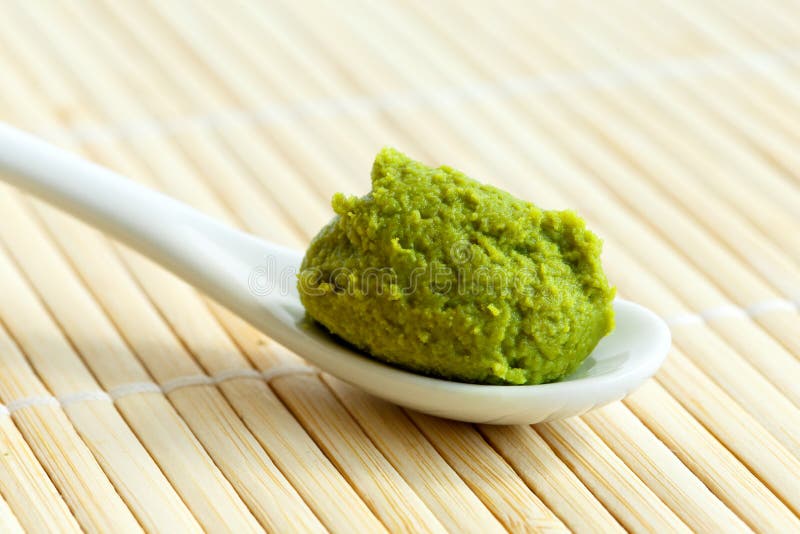 Wasabi paste on ceramic spoon on bamboo mat.