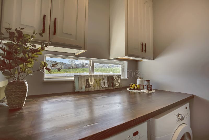 Waschkücheinnenraum mit Kabinetten und Fenster über dem braunen hölzernen Countertop lizenzfreie stockbilder Waschkücheinnenraum mit Kabinetten und Fenster über dem braunen hölzernen Countertop lizenzfreie stockbilder