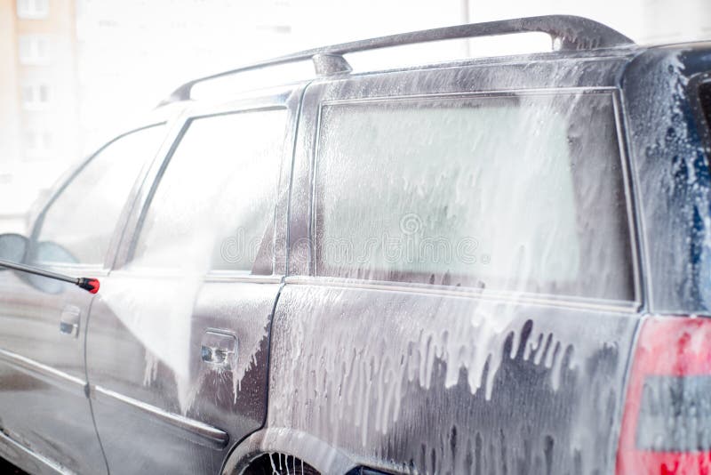 Car Wash, Plenty of Water and Foam. Drops Drip Down the Windows of the
