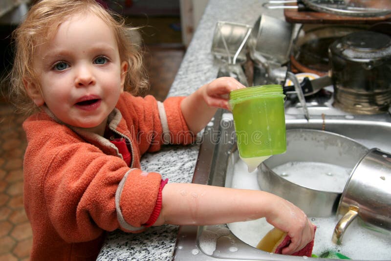 Bambino a lavare i piatti in cucina.