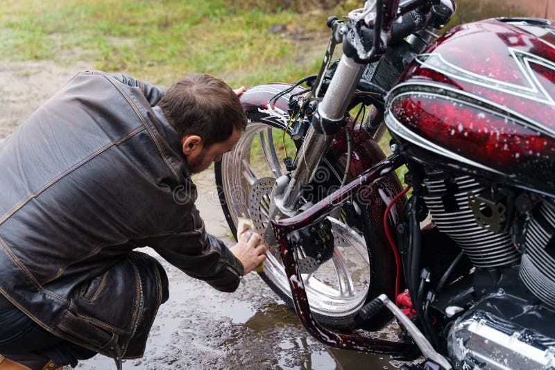 Washing a Motorcycle Engine with a Detergent Using a Sponge. Stock