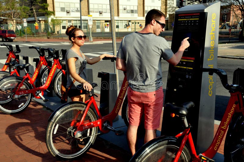 Washington, DC: Young couple renting a bicycle at a Washington Capitol Bike Share docking station on North Carolina Avenue S.E. Washington, DC: Young couple renting a bicycle at a Washington Capitol Bike Share docking station on North Carolina Avenue S.E.