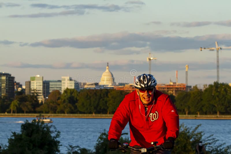 A cyclist wearing Washington Nationals baseball team hoodie with Capitol hill in background