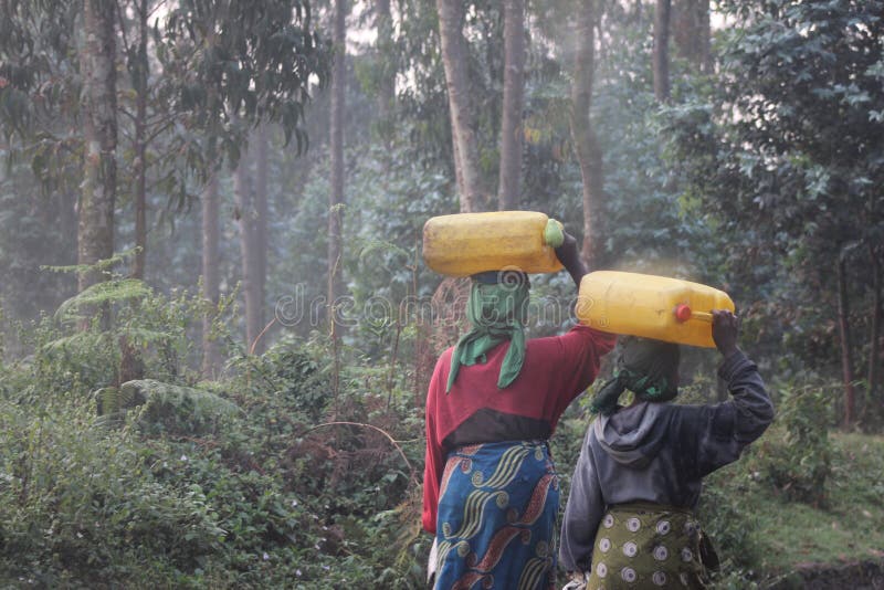 Two women carrying bottles of water on their head in Rwanda . Two women carrying bottles of water on their head in Rwanda .