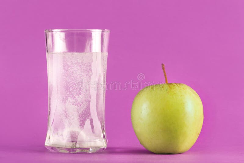 Wasserglas mit schäumender Tablette mit Blasen und grünem Apfel stockbild Wasserglas mit schäumender Tablette mit Blasen und grünem Apfel stockbild