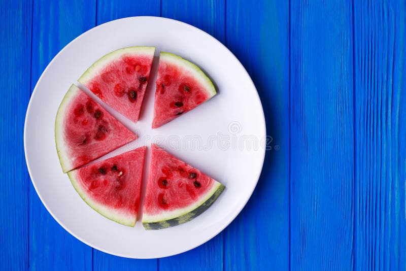 Wassermelonenscheiben auf einer weißen Platte auf blauem hölzernem Hintergrund, Franc stockbild Wassermelonenscheiben auf einer weißen Platte auf blauem hölzernem Hintergrund, Franc stockbild