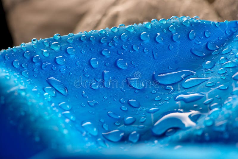 Wassertropfen auf wasserdichtem blauem Nylongewebe Makrodetailansicht der gesponnenen synthetischen Regenbekleidung Schwerer unsc lizenzfreies stockfoto Wassertropfen auf wasserdichtem blauem Nylongewebe Makrodetailansicht der gesponnenen synthetischen Regenbekleidung Schwerer unsc lizenzfreies stockfoto