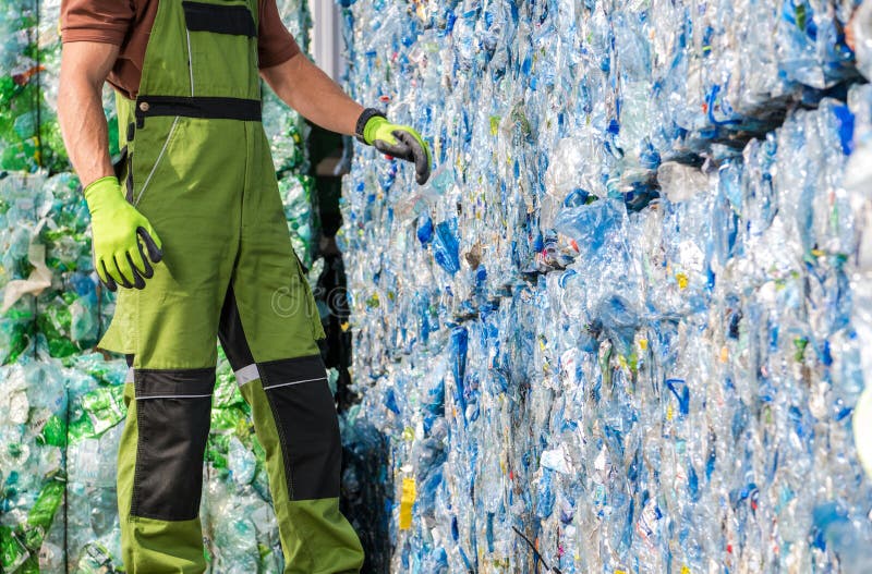 Waste Management Worker in Front of a Pile of Pressed Plastic PET