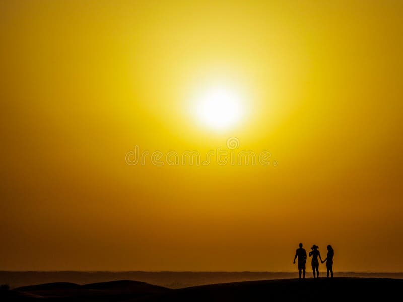 Asombroso atardecer en desierto tres de pie sobre el dunas a seguimiento.