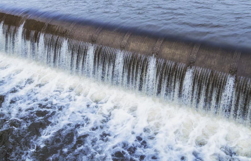 Water cascade streaming down a lasher of dam, water saving concept