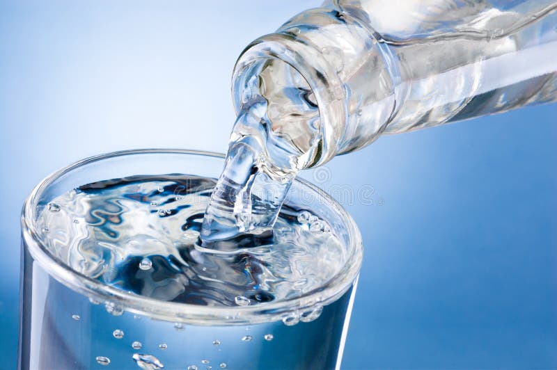 Water poured out of bottle into a glass isolated on white background. Water poured out of bottle into a glass isolated on white background