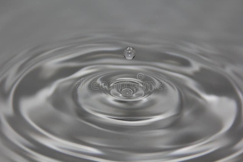 Water Drop Suspended Over Gray Water Stock Photos Free & RoyaltyFree