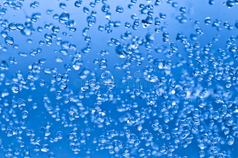 Gocce d'acqua a sguazzare nell'aria di fronte a sfondo blu.