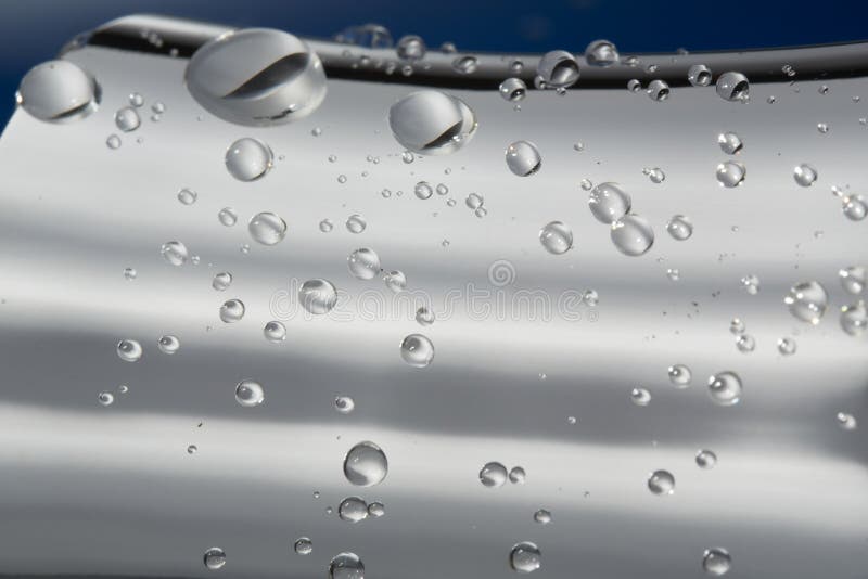 Water drops on a silver metallic surface with blue background