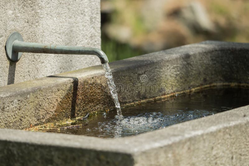 Water flows from a tap at the stone fountain