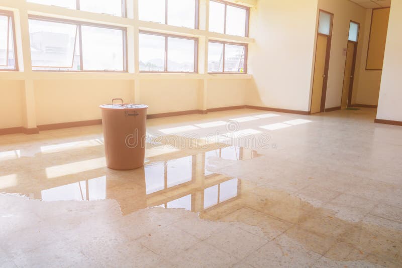 Water leak drop interior office building in red bucket from Ceiling and flow on terrazzo floor