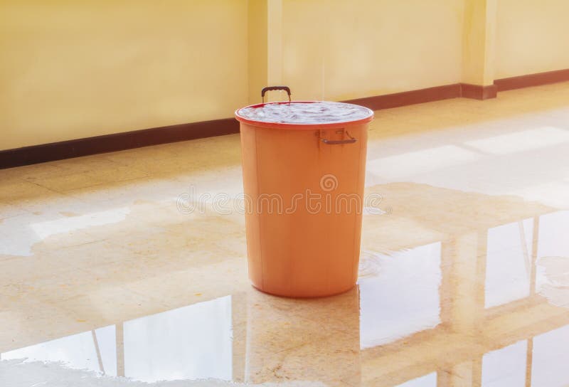 Water leak drop interior office building in red bucket from Ceiling and flow on terrazzo floor