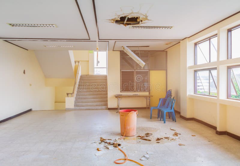 Water leak drop interior office building in red bucket from gypsum ceiling and flow on terrazzo floor