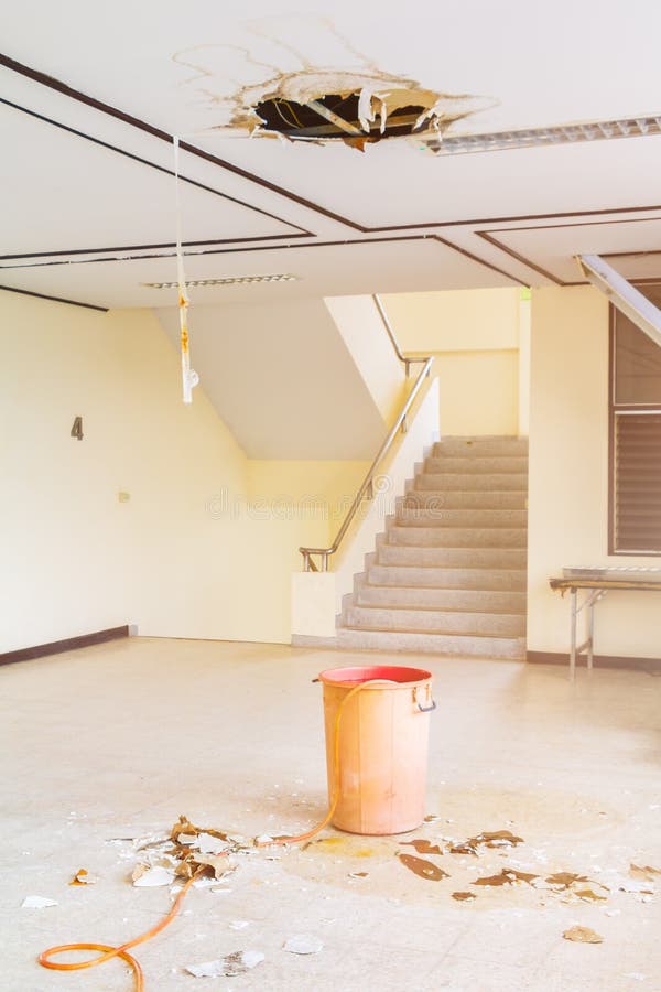 Water leak drop in red tank interior office building in from ceiling and flow on terrazzo floor