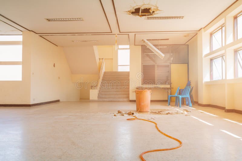 Water leak drop in red tank interior office building in from ceiling and flow on terrazzo floor