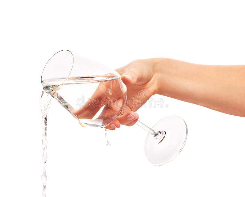 Water pouring from full wine glass in woman's hand stock photo