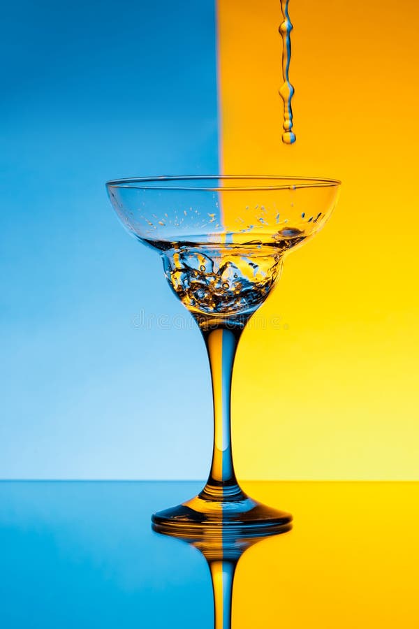 Water Pouring in Glass Over Blue and Yellow Background. Stock Photo Image of blue, neon 80072052