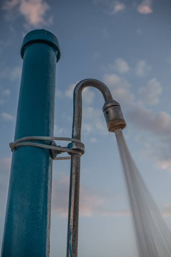 Water Pouring from Shower Head. Public Shower for Outdoor swimming under the Blue Cloudy Sky. Closeup Angle Shot of Pipe stock photos Water Pouring from Shower Head. Public Shower for Outdoor swimming under the Blue Cloudy Sky. Closeup Angle Shot of Pipe stock photos