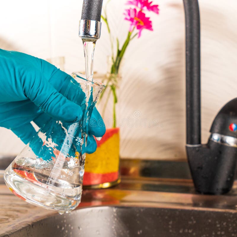 Water Purification Specialist Tap Water Pours into a Glass Flask. Stock