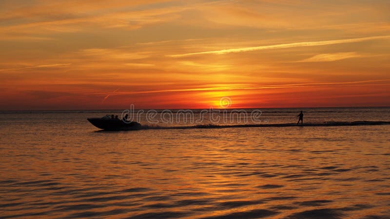 Water skiing in sea at orange sunset