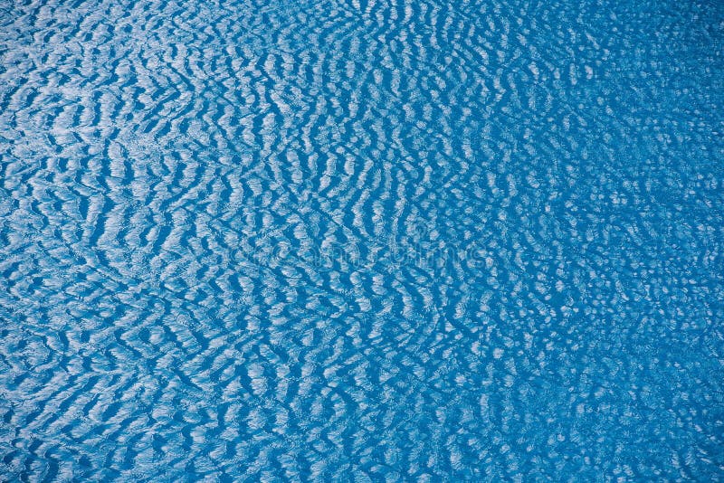 Water with small waves and raindrops on a pool with blue texture background