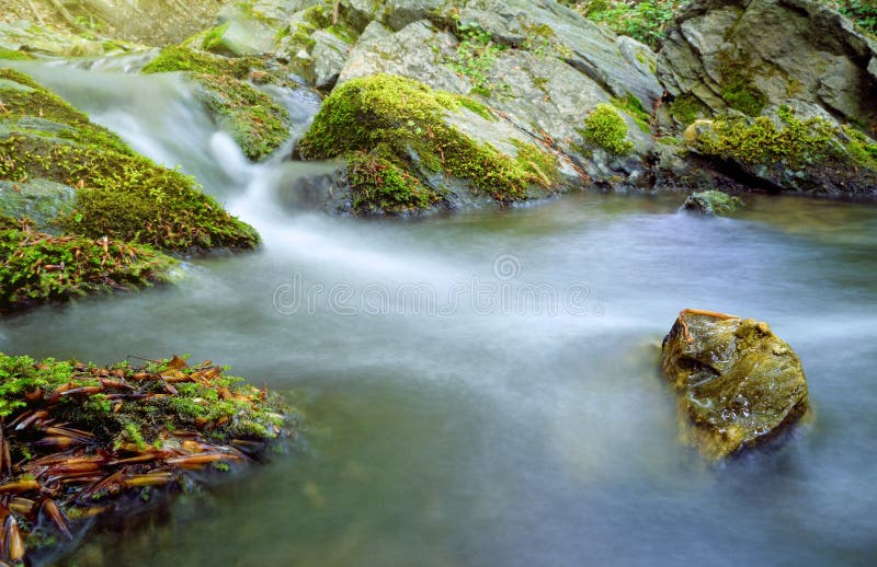 Water Stream Cascades With Green Moss And Rock In Water Stock Photo