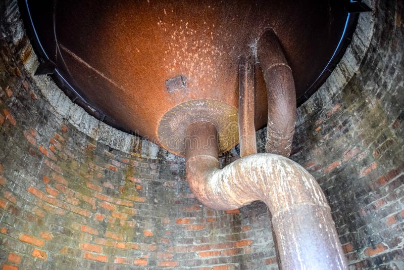 Water tank of old water tower. Rusty tank and pipes of the water system