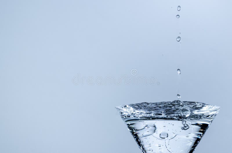 Waterdrops Dropping into a Glass Filled with Water Stock Photo Image