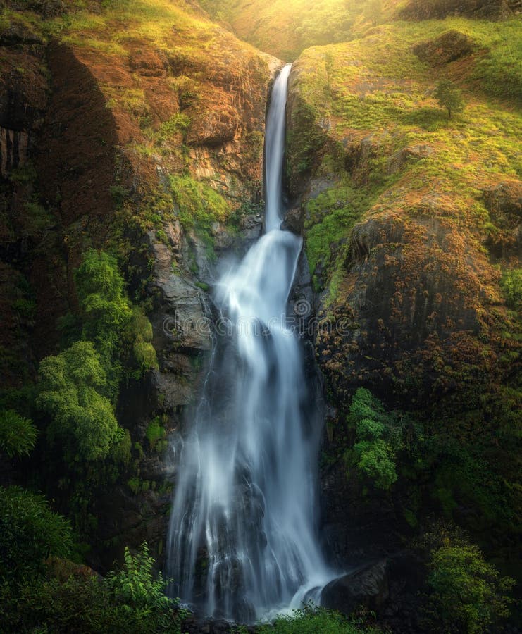 Waterfall in autumn forest at sunset in Nepal. Colorful landscape