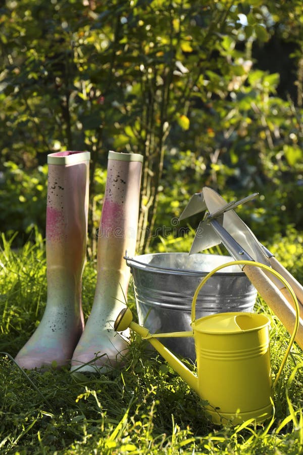 Watering Can, Gardening Tools and Rubber Boots on Green Grass Outdoors