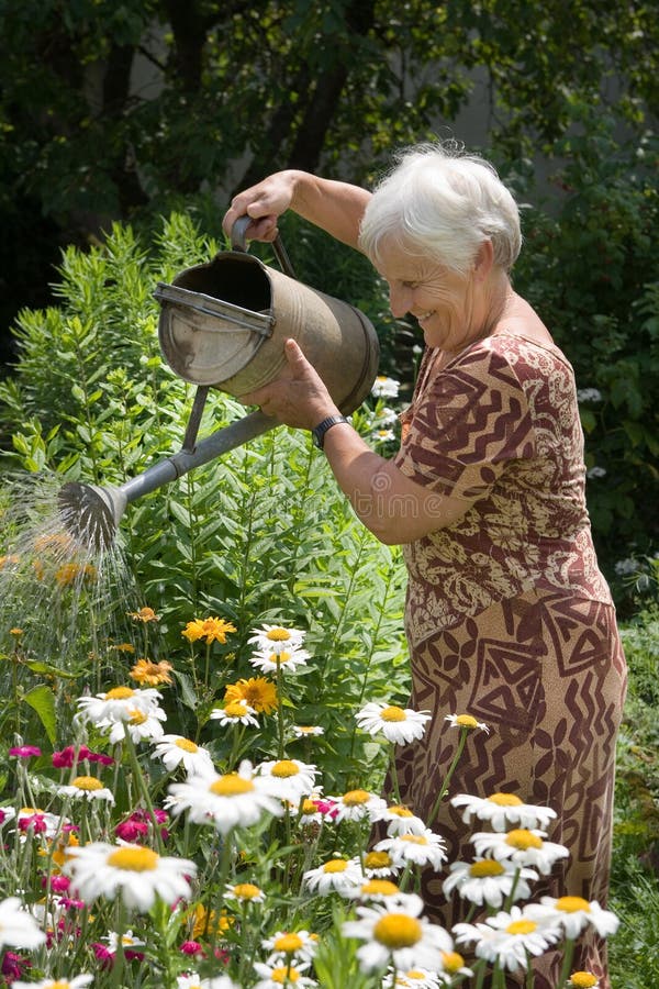 Grandmom annaffia i fiori nel suo giardino.