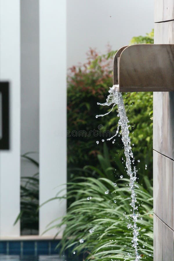 Waterstraal die in het zwembad vallen Zwembad dat van palmen in de yard van villa wordt omringd stock foto Waterstraal die in het zwembad vallen Zwembad dat van palmen in de yard van villa wordt omringd stock foto