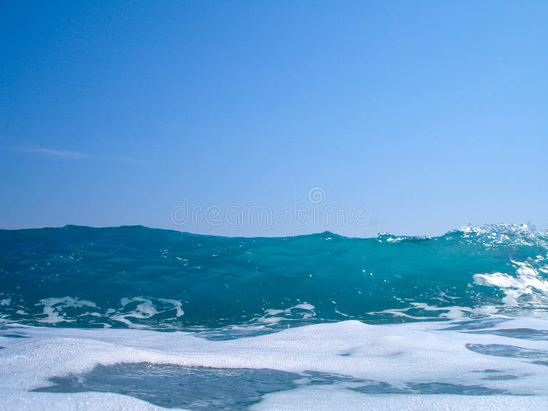 Wave breaking on blue sky royalty free stock photography