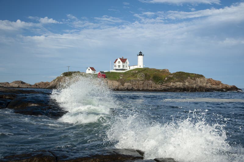 Waves Break Around Nubble Lighthouse on a Summer Day in Maine. Waves break during high tide in front of Nubble Cape Neddick lighthouse on a warm summer day in