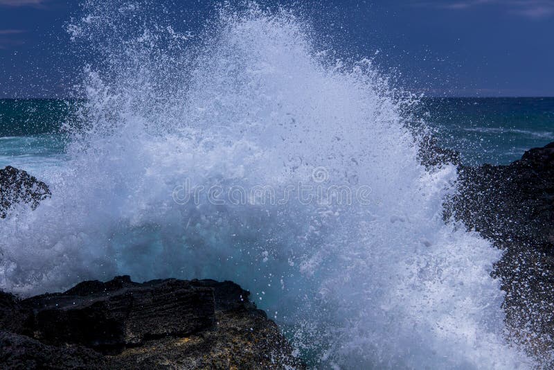 Waves break on volcanic rocks