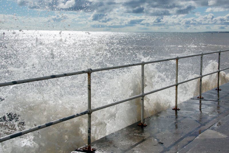 Waves breaking over the sea wall. Large Waves breaking over the sea wall. Droplets of seawater glinting in the sun. This is at Hornsea, East Yorkshire, UK stock image Waves breaking over the sea wall. Large Waves breaking over the sea wall. Droplets of seawater glinting in the sun. This is at Hornsea, East Yorkshire, UK stock image