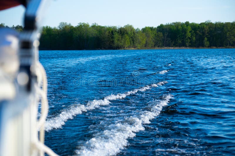 Waves from pontoon boat on aqua blue lake