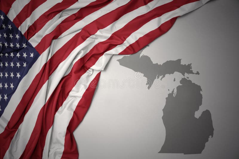 Waving colorful national flag of united states of america on a gray michigan state map background.