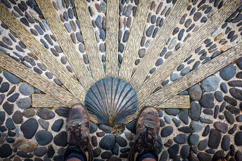 The way of saint James or compostelle. well worn Walking shoes with scallop shell. Nasbinals Lozere,France stock photo
