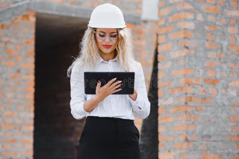 Wchłonięta przez kobietę inżyniera pracującą z tabletką na tle placu budowy. portret zdjęcia stock