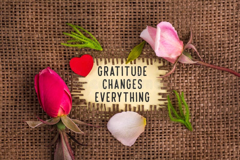 Gratitude changes everything written in hole on the burlap with rose flowers and wooden red heart. Gratitude changes everything written in hole on the burlap with rose flowers and wooden red heart