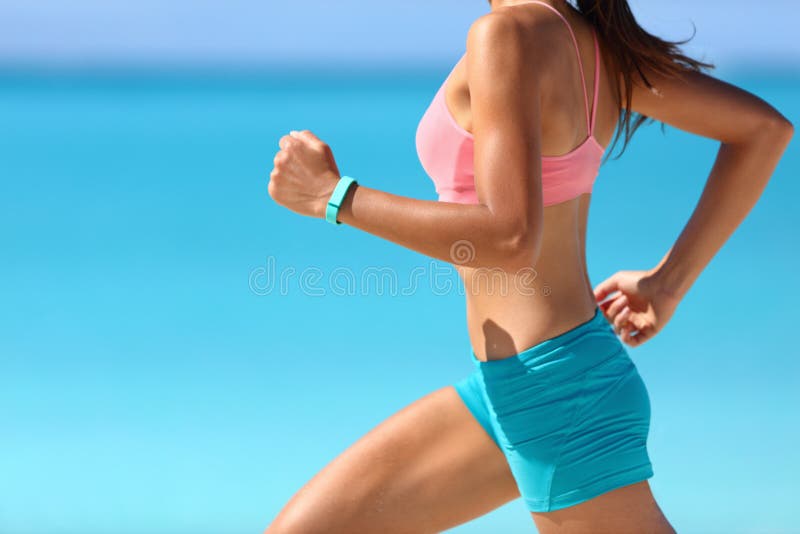 Runner woman running on beach with watch and sports bra top. Beautiful fit  female fitness model training and working out outside in summer at part of  healthy lifestyle Stock Photo
