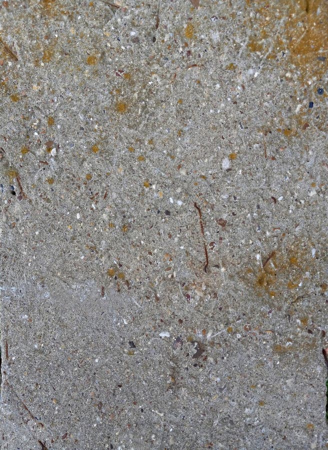 A weathered light gray cement block surface with coarse texture and mixture of small embedded pebbles in brown black reddish white foto de stock royalty free