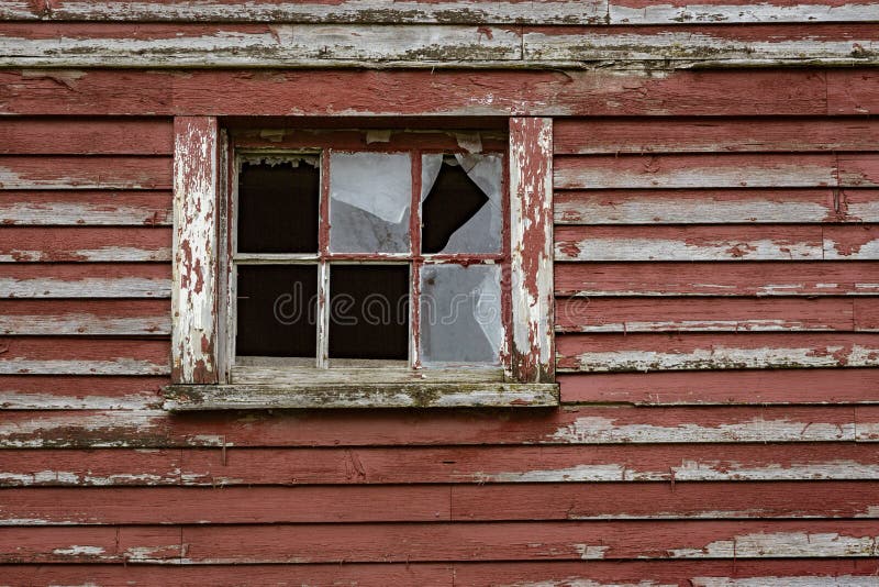 Weathered red paint and broken windows are a common site on barns stock image